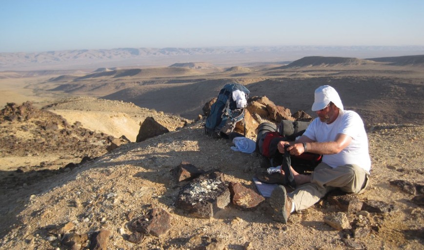 Don taking care of his feet after breakfast with the Machtesh haGadol in the distance.